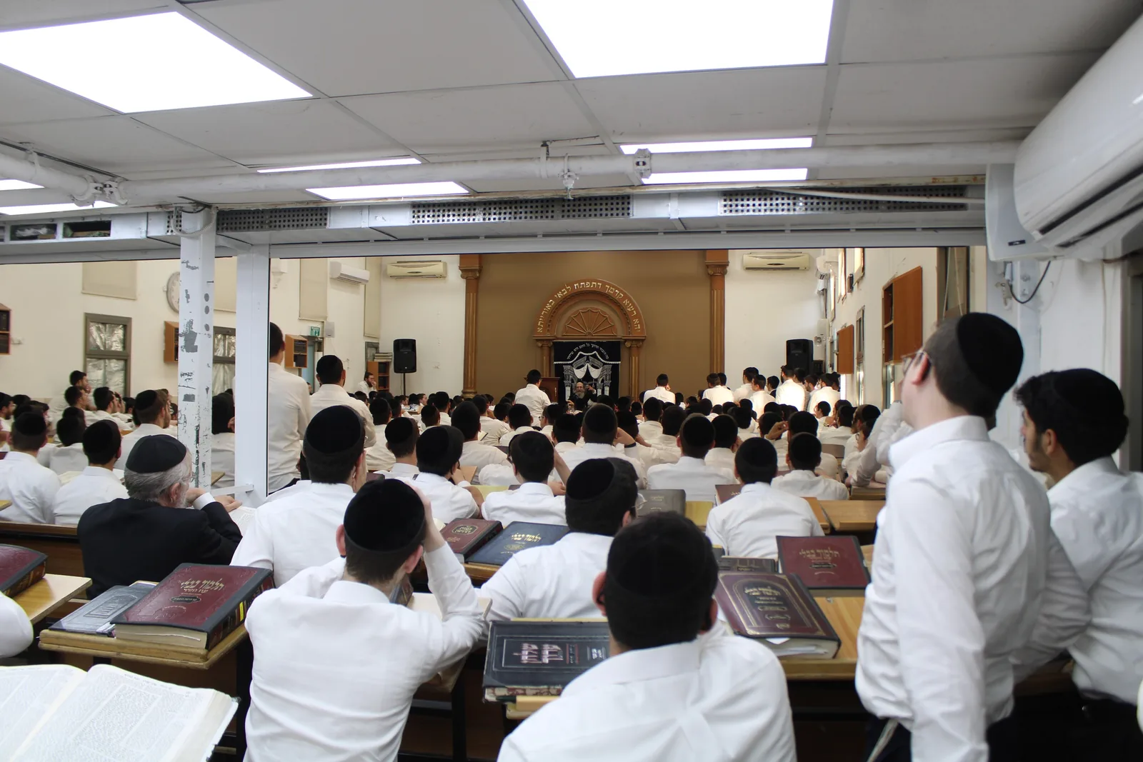 בית המדרש מלא בשעת שיעור, בחורי הישיבה יושבים מול גמרות פתוחות